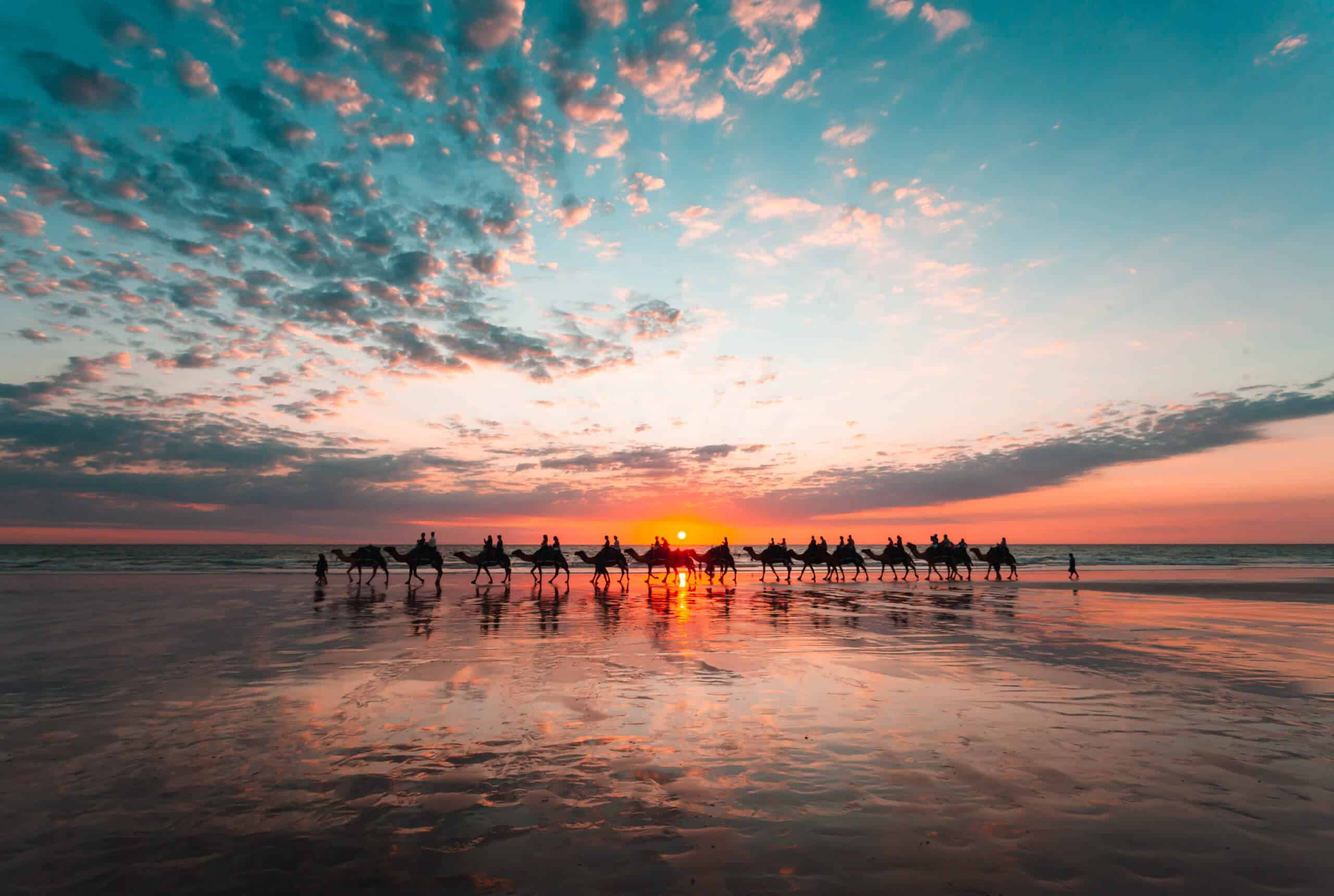A beautiful beach in Broome, Western Australia, with the sun setting and the silhouette of camels.