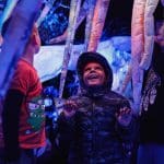 A photo of a young boy, looking up towards the ceiling in excitement.